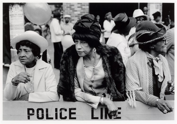 PFF202-Dawoud Bey, Three Women at a Parade, 1978. Black and white photograph of three older black women leaning on a parade barricade.