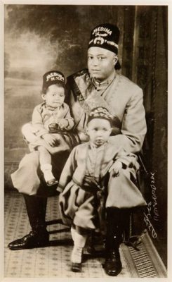 FF211-James VanDerZee, Masons, 1926. Black and white family portrait with man in Mason regalia with two children in matching attire.